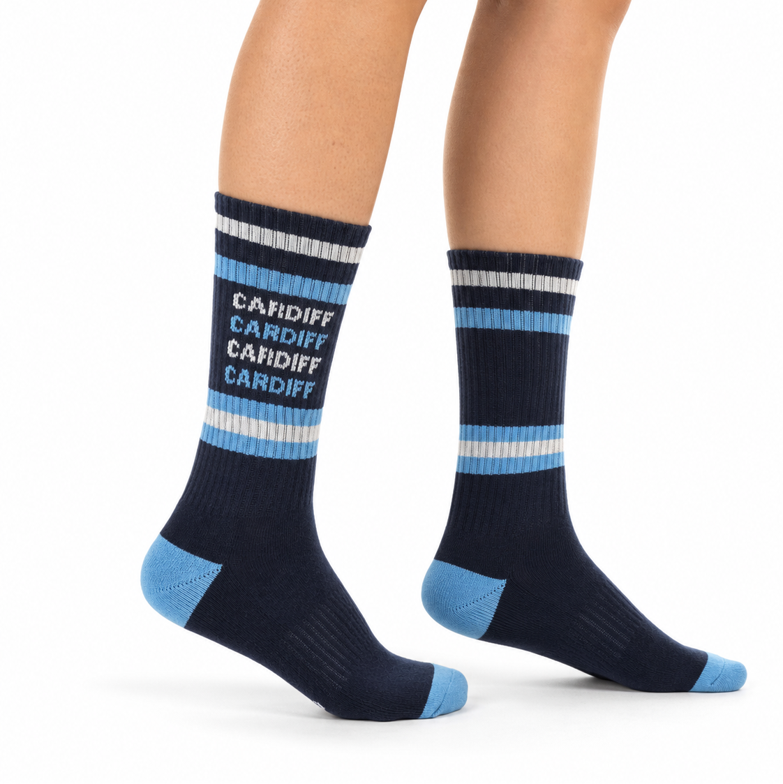 A person's legs wearing navy crew socks with light blue and white stripes, featuring the word 'CARDIFF' printed in white on the front.