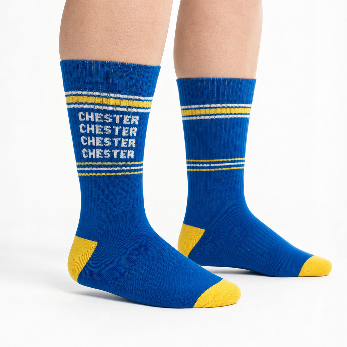A person's legs wearing blue crew socks with yellow accents and the word 'CHESTER' printed in white on the front.