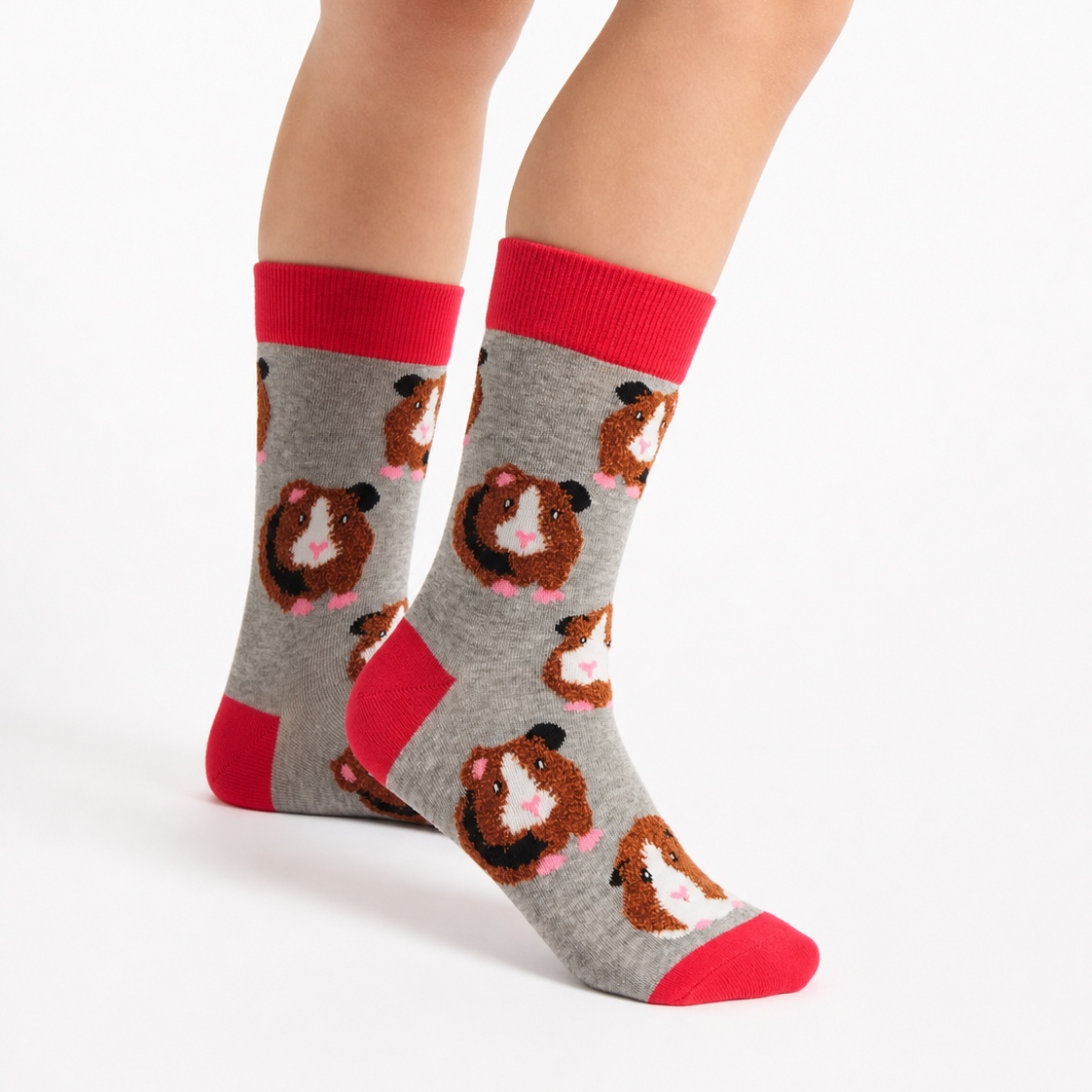 A pair of crew socks worn on a person's feet, featuring a gray background with a repeating pattern of brown and white hamsters, bright red cuffs, heels, and toes, shown against a plain white studio background.
