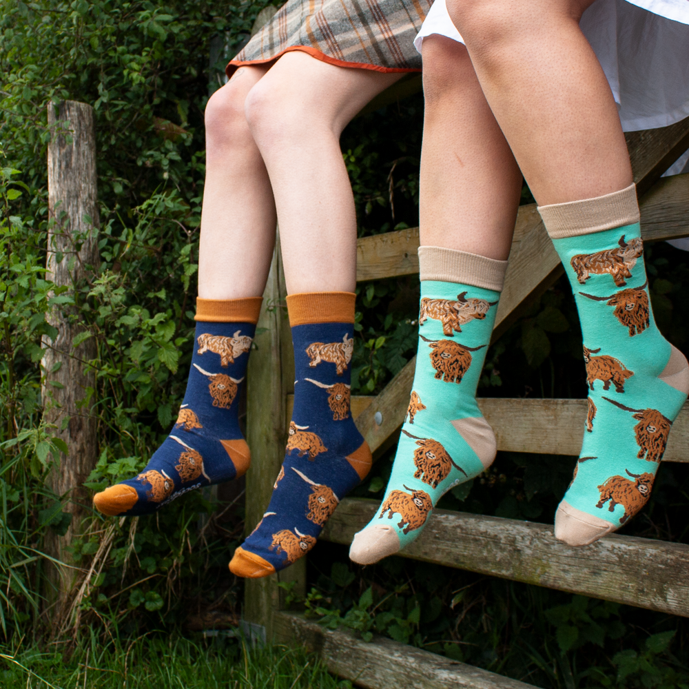 People sitting on a farm gate wearing Soctopus socks. 