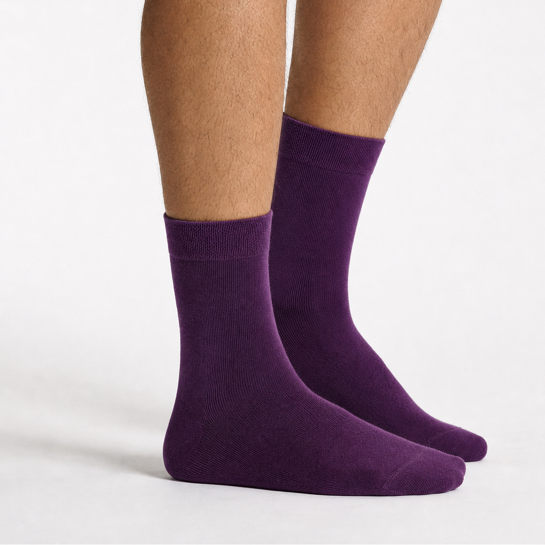 A pair of solid purple crew socks worn on a person's feet, shown against a clean white studio background.