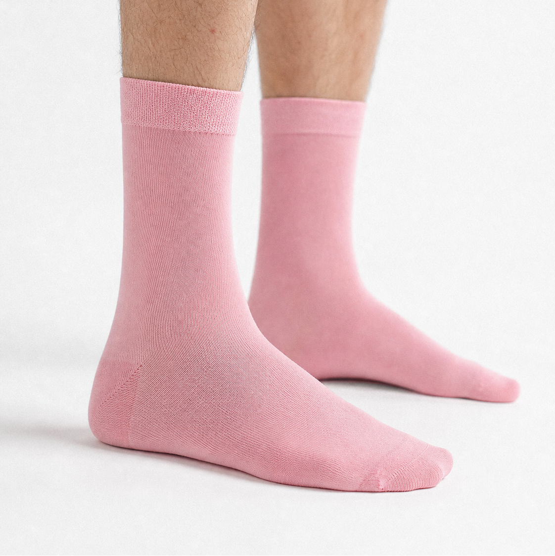 A pair of light pink crew socks worn on a person's feet, shown against a clean white studio background.
