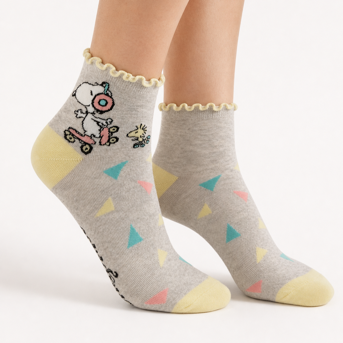 A pair of ankle socks featuring Snoopy on roller skates with Woodstock hot on his heals. Yellow heel and toe. 