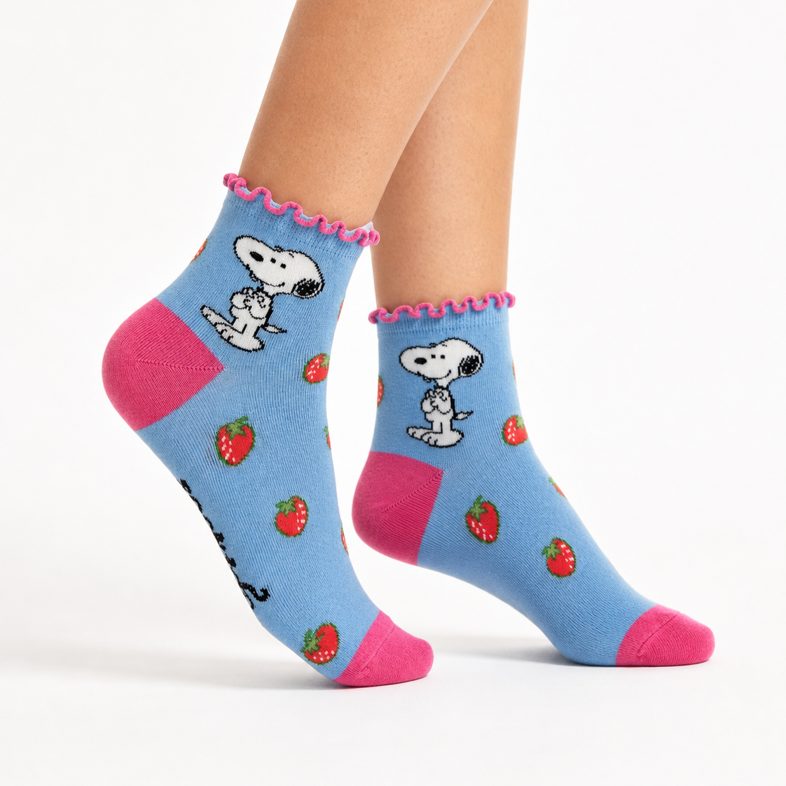 A pair of light blue ankle socks with pink ruffled trim, featuring a cartoon dog character and strawberry pattern, modeled on feet against a white background.