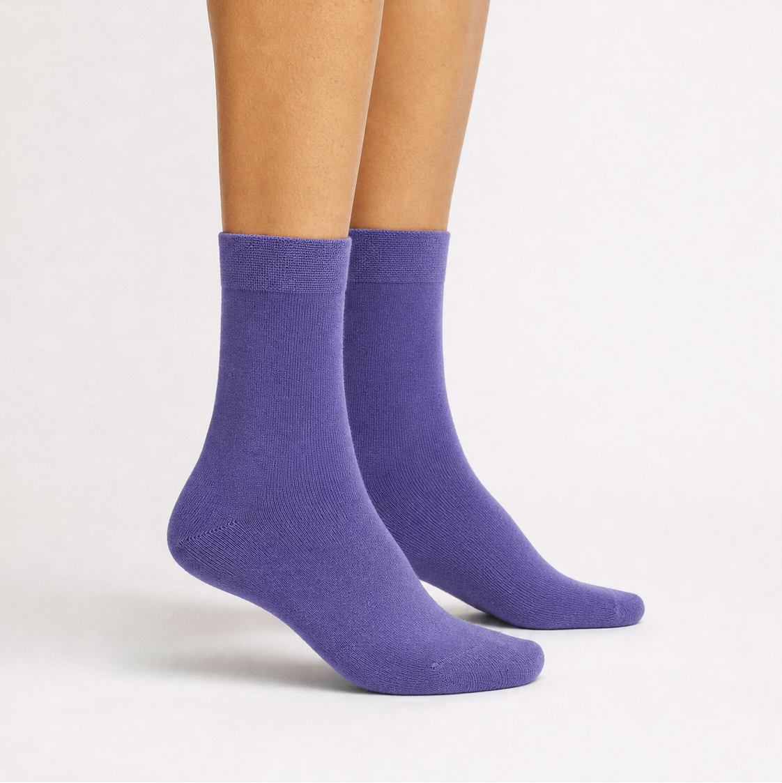 A pair of mid-calf purple socks worn on a model's feet, shown against a clean white studio background.