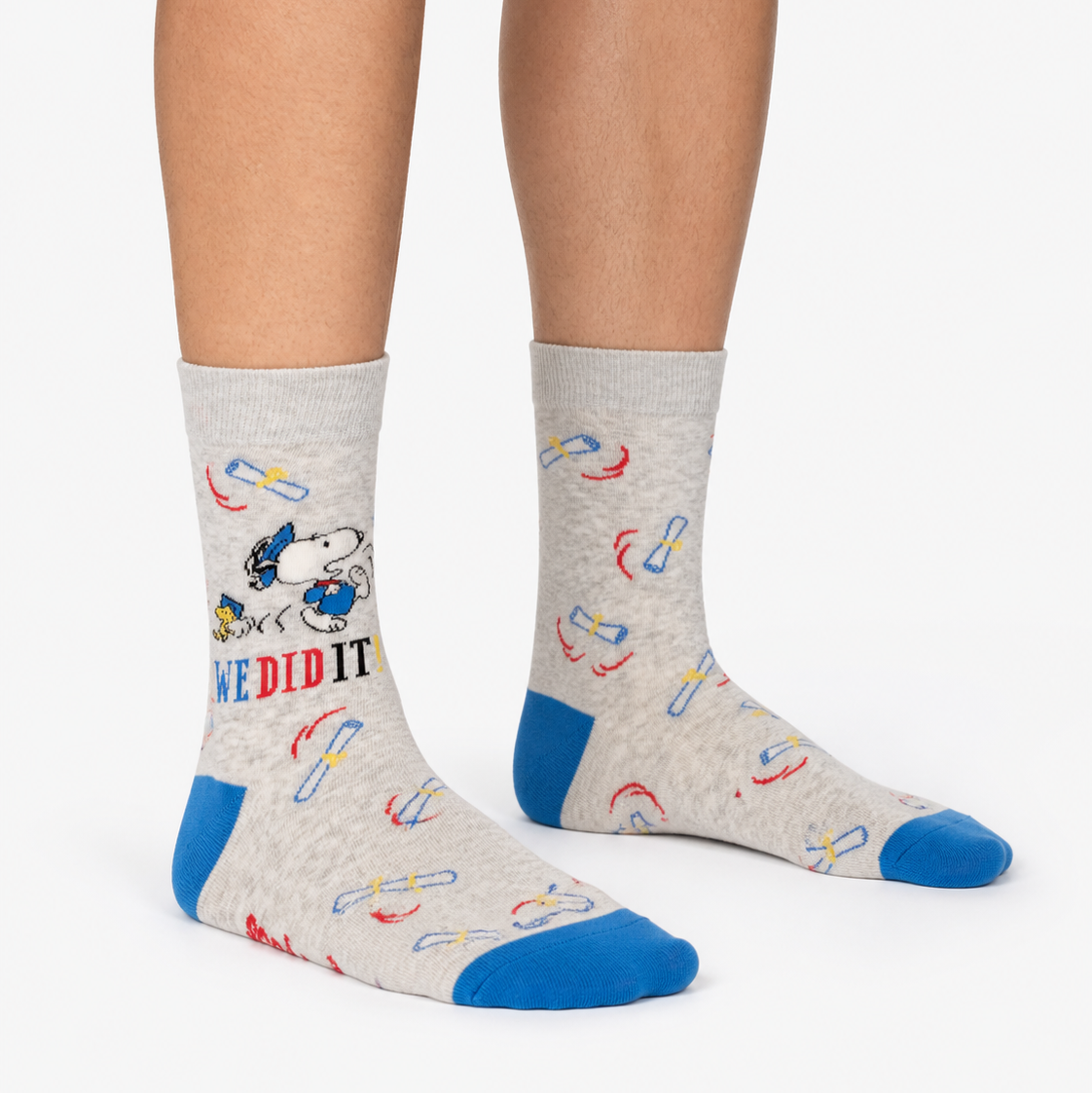 A pair of socks featuring Snoopy and Woodstock on a grey background with blue toe and heel. 