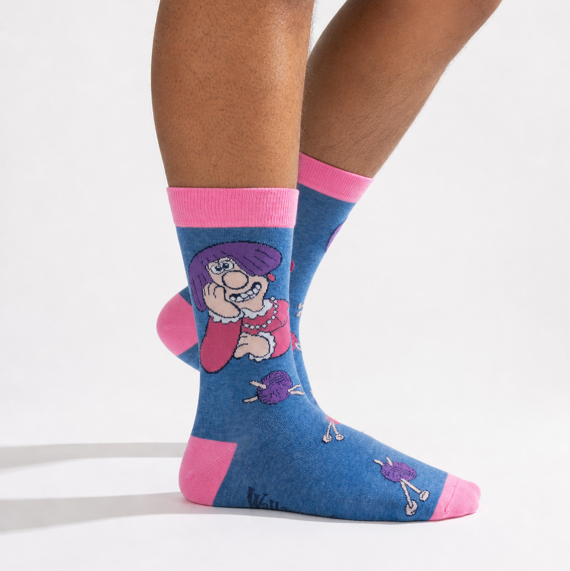 A person wearing blue crew socks with pink cuffs, heels, and toes, featuring a cartoon character printed on the side.